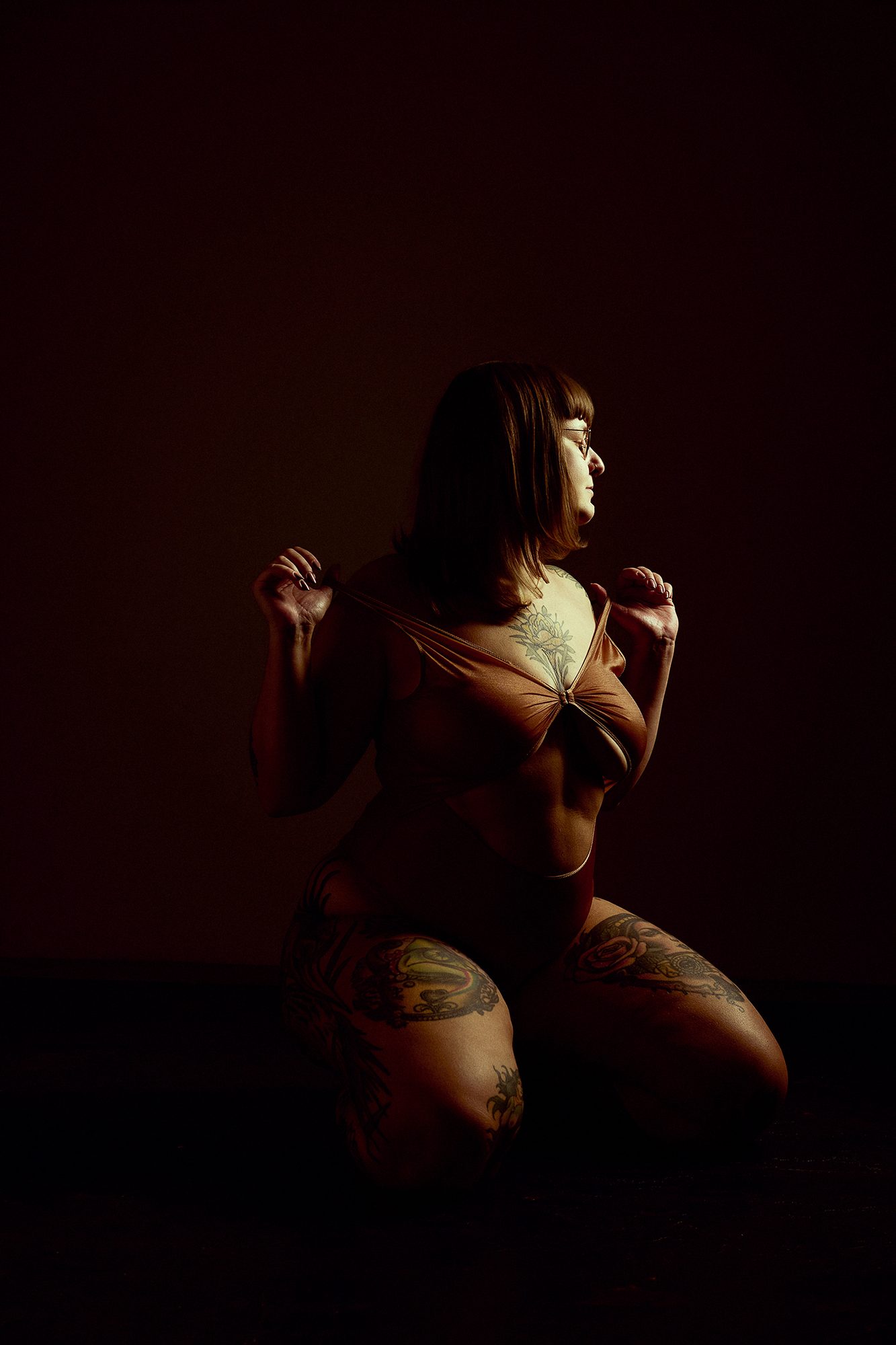 Boudoirportret op de rug in zwarte lingerie met jarretel in donkere setting